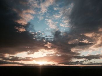 Scenic view of silhouette field against dramatic sky