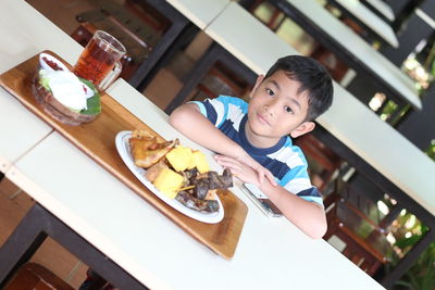 High angle view of boy with food on table sitting in restaurant