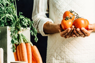 Midsection of woman holding tomatoes