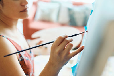 Midsection of woman painting on easel