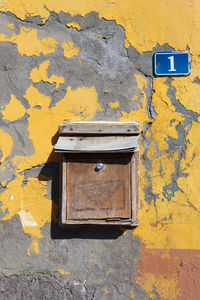 Close-up of yellow mailbox on weathered wall