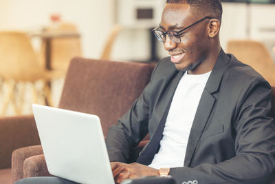 A black man works on a tablet computer in the hotel lobby.