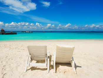 Chair on beach against blue sky