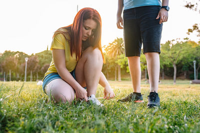 Woman tying shoelace on grass at park