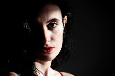 Close-up portrait of young woman against black background