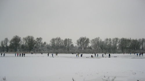 People on snow covered landscape against clear sky