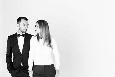 Elegant man looking at thoughtful woman against white background