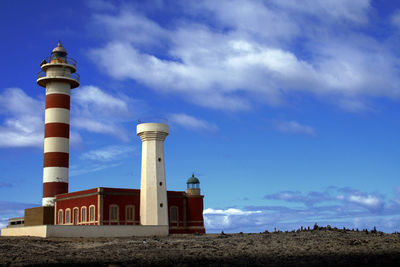 Low angle view of lighthouse by buildings against sky