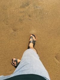 Low section of man standing on sand at beach