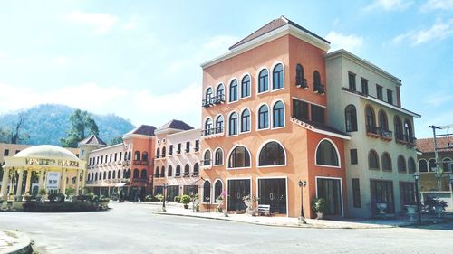 Residential buildings by street in town against sky