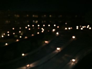 Defocused image of illuminated city against sky at night