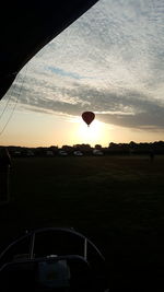 Hot air balloons on field against sky during sunset