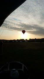Hot air balloons on field against sky during sunset