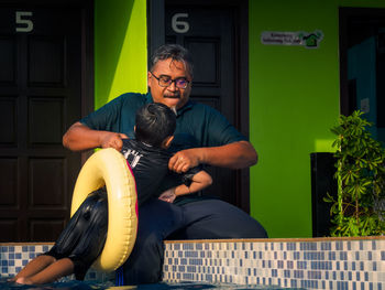 Full length of father with daughter sitting outdoors