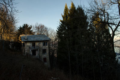 House amidst trees and plants in forest against sky
