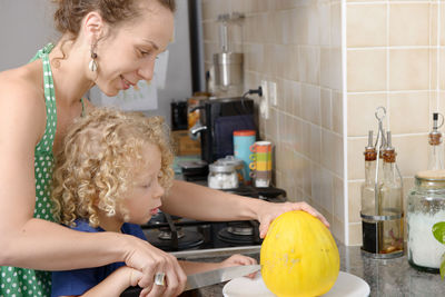 Mother and son cutting fruit in kitchen