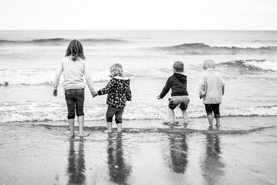 Rear view of siblings enjoying at beach