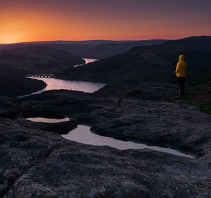 Woman standing on mountain against sky during sunset