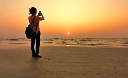 Man photographing at beach during sunset