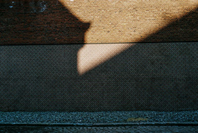 Close-up low section of shadow on tiled floor