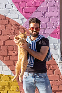 Young man wearing sunglasses standing against brick wall