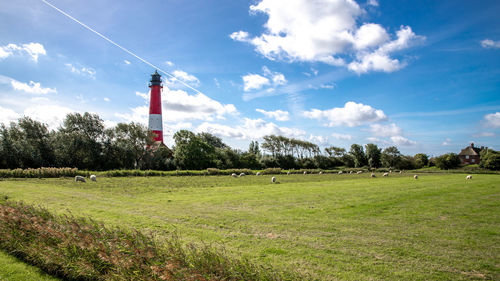 Lighthouse on field against sky