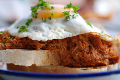 Close-up of pork with fried egg and bread in plate