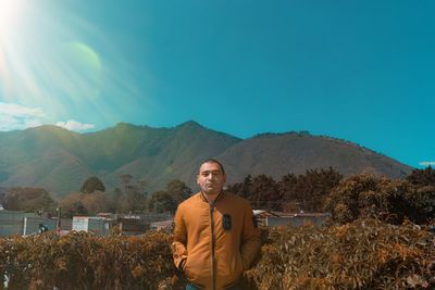 Portrait of smiling man standing on mountain against sky