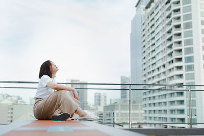 Solo asian woman sit and breatheduring outdoor break and relax at rooftop with city background