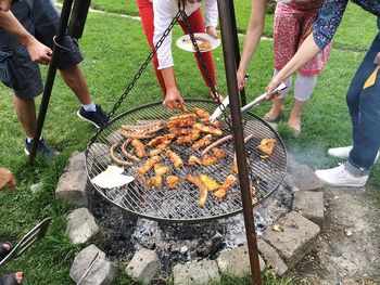 Low section of people standing on barbecue grill