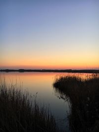 Scenic view of lake against clear sky during sunset