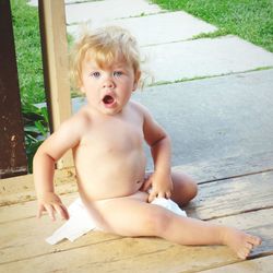 Portrait of shirtless baby sitting outdoors