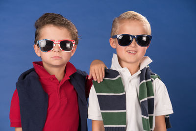 Portrait of siblings wearing sunglasses against blue background