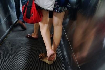 Low section of people walking on escalator