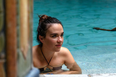 Beautiful young woman relaxing in swimming pool in spa.