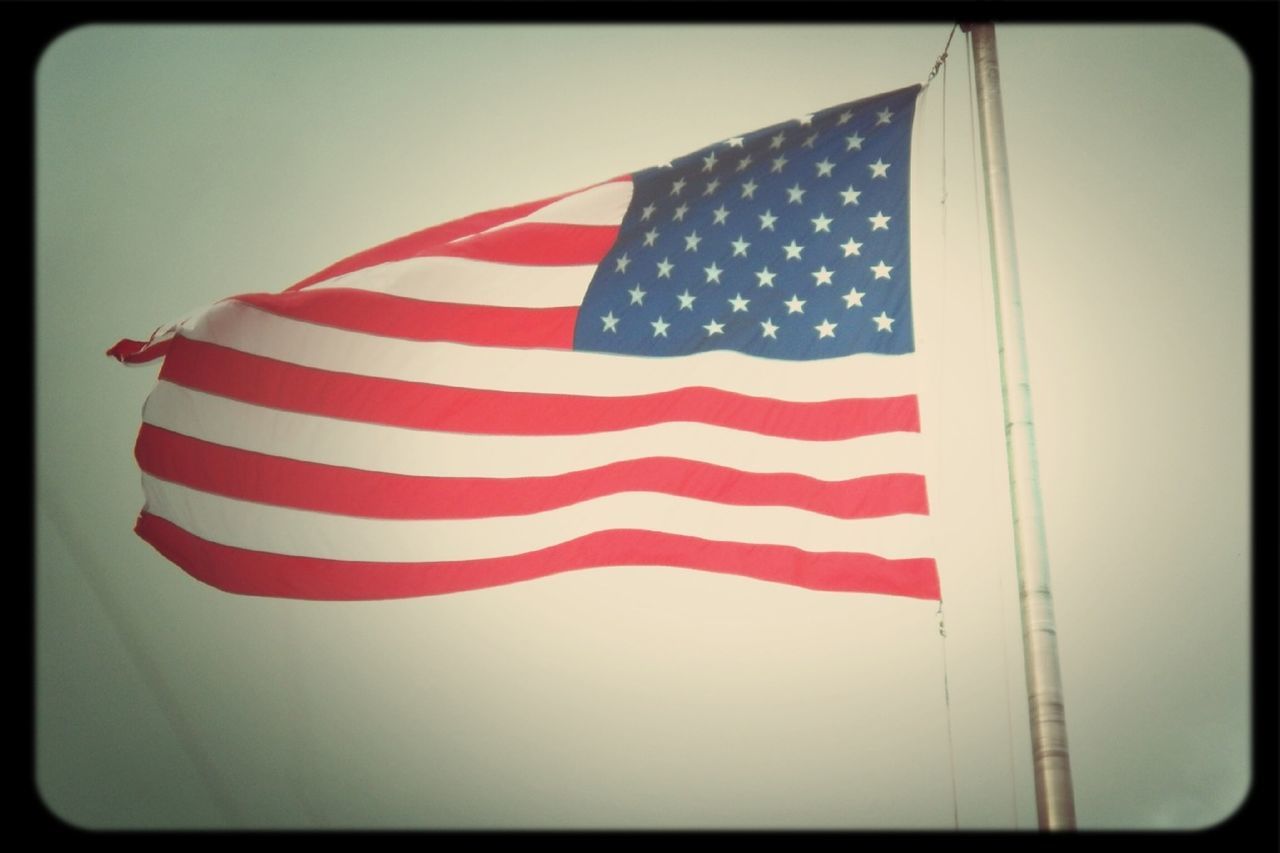 patriotism, flag, national flag, identity, american flag, striped, culture, red, low angle view, star shape, pride, wind, transfer print, flag pole, pole, auto post production filter, sky, white color, stars and stripes, waving