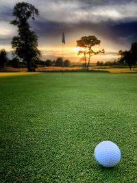 Golf ball on field against sky during sunset