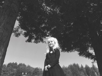 Low angle view of girl standing by tree