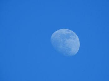 Low angle view of moon against clear blue sky