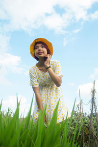 Smiling woman standing on field against sky