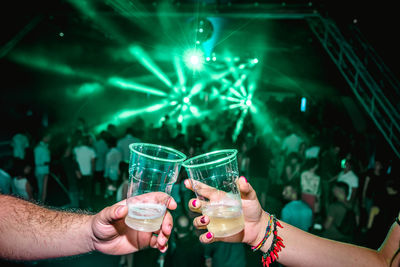 Cropped hands of friends holding drinks in nightclub