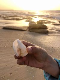 Close-up of hand holding sand at beach against sky