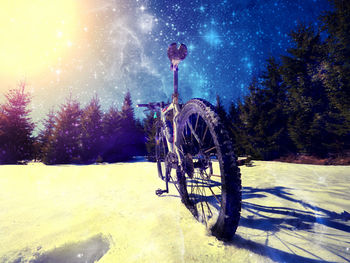 Bicycle on snow covered field against sky