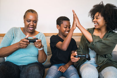 Happy family playing video game while sitting on sofa at home