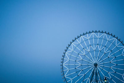 Low angle view of ferris wheel against clear blue sky