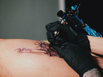 Young woman tattooing statue of liberty man on calf at parlor