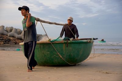 Men walking with boat at beach