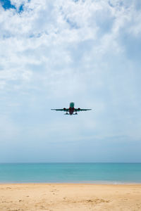 Airplane flying over sea against sky