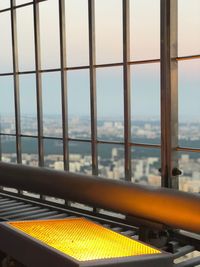 Close-up of yellow railing against sky seen through window