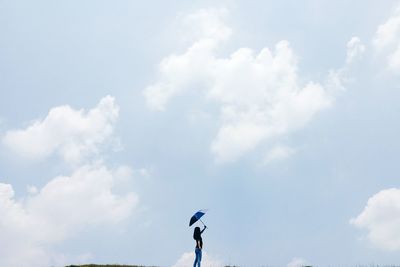 View of woman holding umbrella against cloudy sky